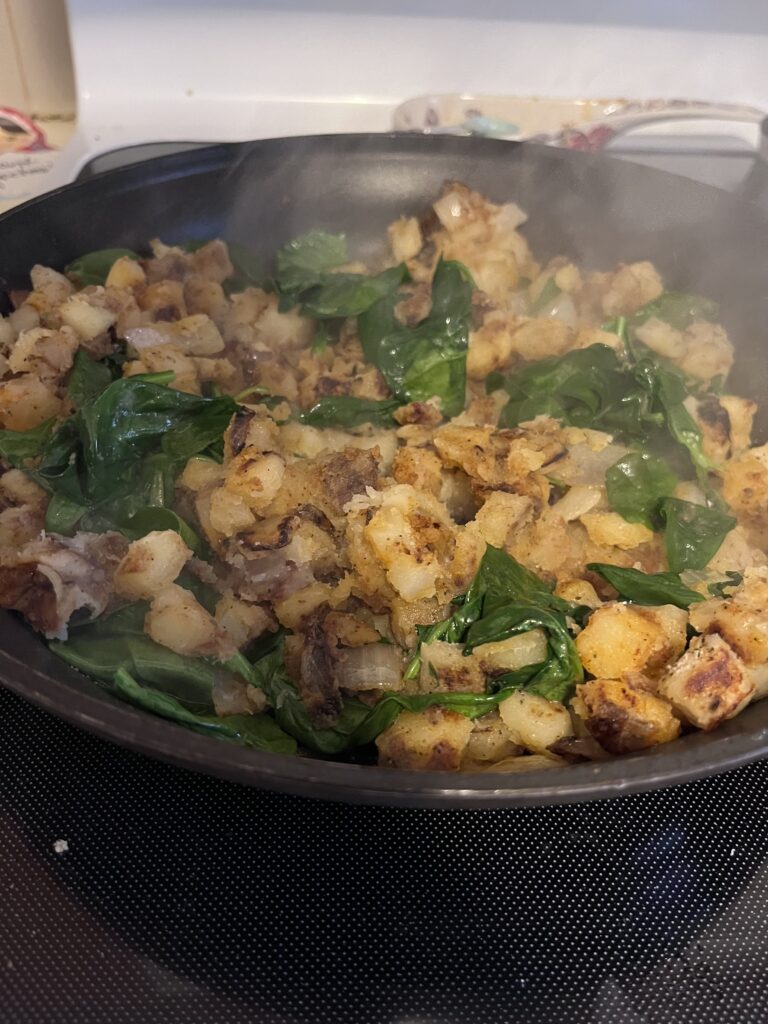 Potato, spinach, and spices in cast iron skillet