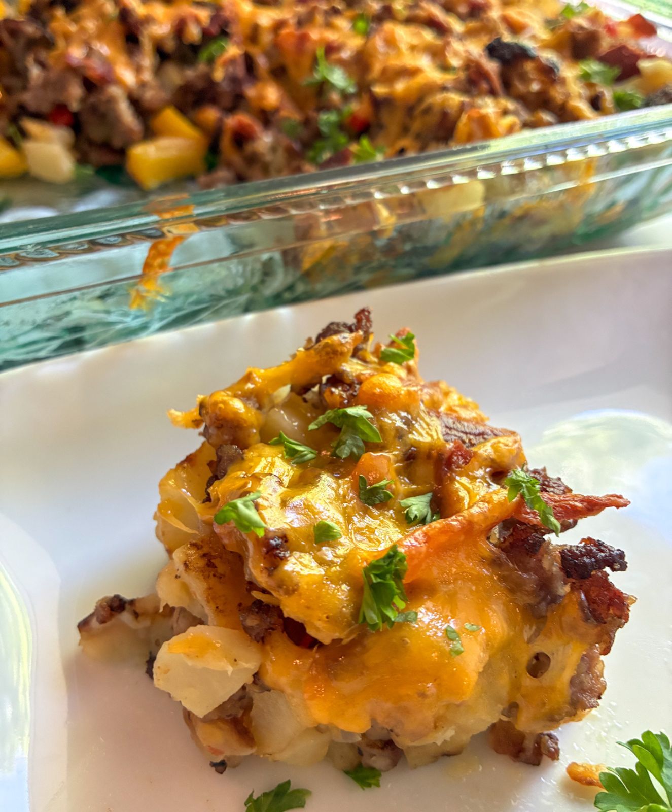 Eggless breakfast casserole slice on a plate with the casserole behind it
