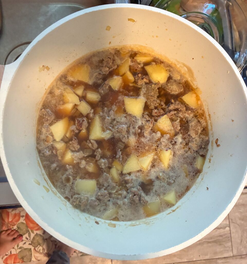 The sausage potato soup after the potato have cooked in beef broth in a large pot