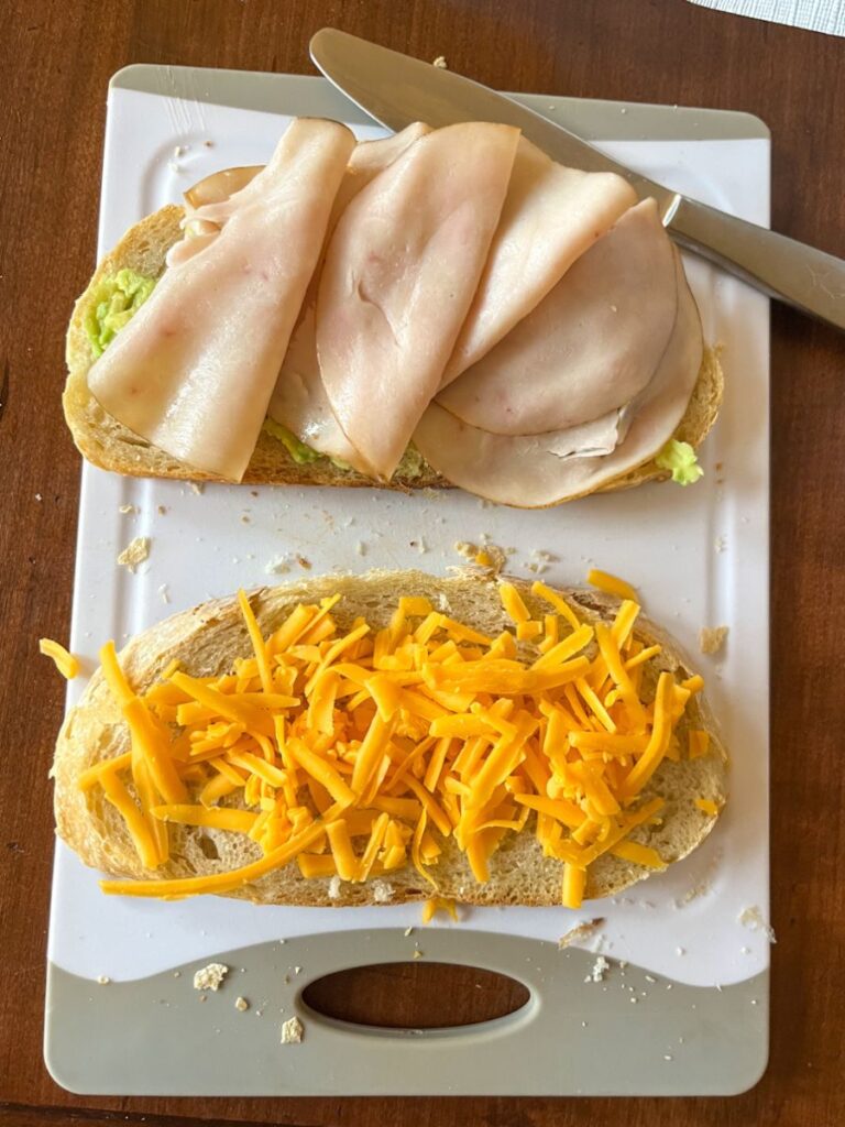 2 slices of sourdough bread, one with turkey on it and one with cheddar cheese