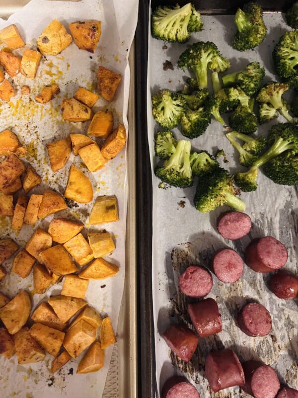 Sheet pan covered in cooked sweet potatoes, broccoli, and turkey sausage