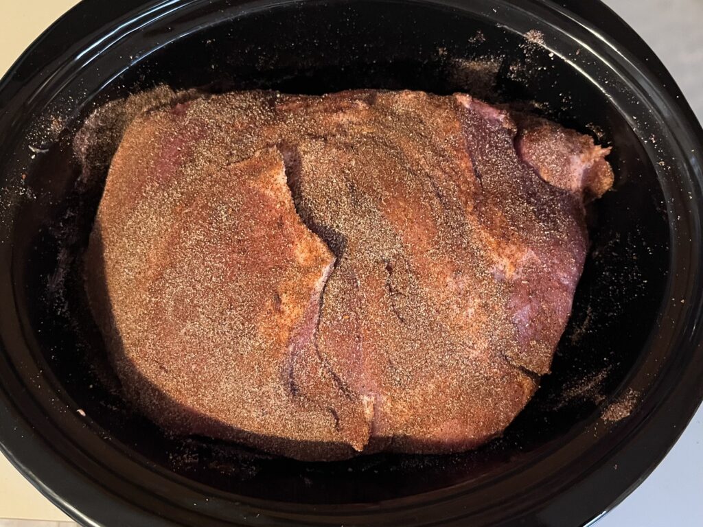 Pork shoulder covered in spices in the slow cooker