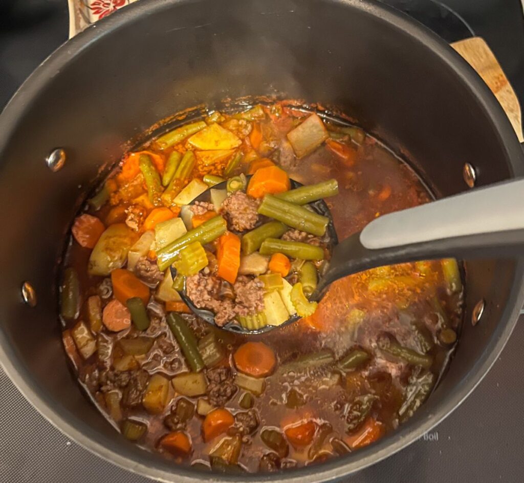 soup with bone broth in a large pot with a ladle scooping some out