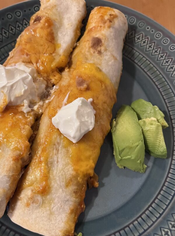 Pork enchiladas served on a plate with slices of avocado