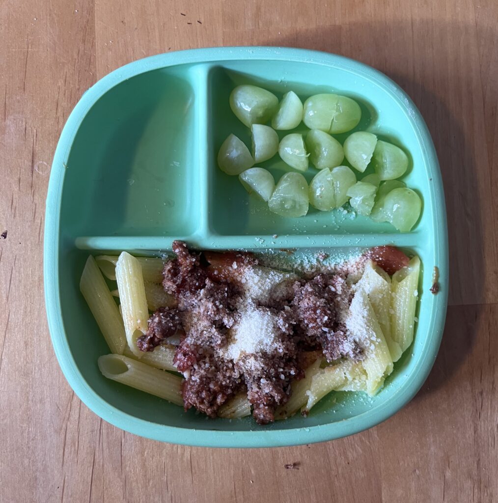 Preschool lunch idea including pasta and meat sauce and green grapes