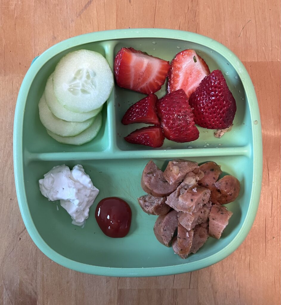 Chicken sausage, sliced cucumber, and strawberries for an easy preschool lunch