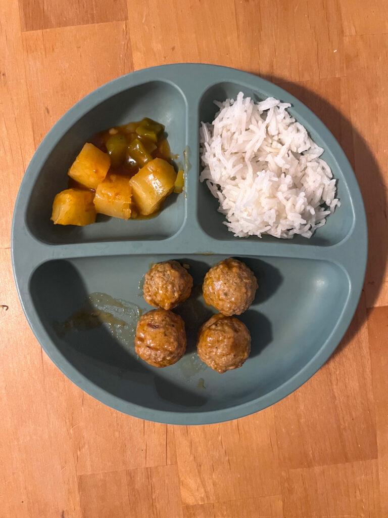 A kids plate filled with sweet and sour meatballs, pineapples and rice