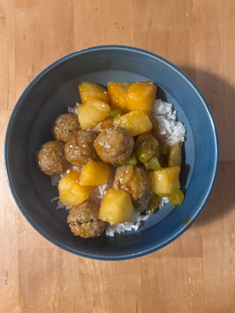 Sweet and sour meatballs served in a bowl over rice