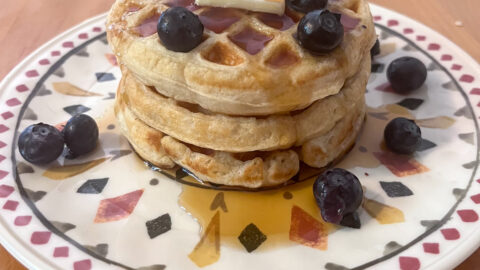 Egg Free Waffles stacked on a plate with blueberries, butter, and maple syrup