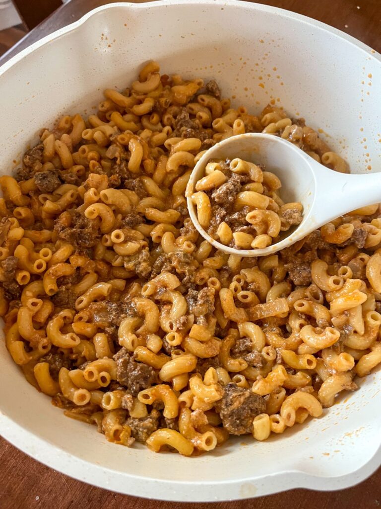 Hamburger helper in a large pot with a spoon scooping it out