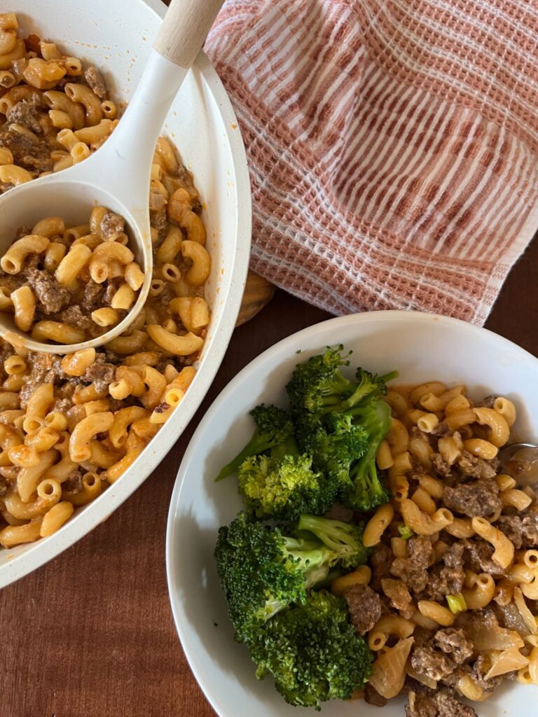 Hamburger helper served in a bowl next to the skillet filled with the dish.