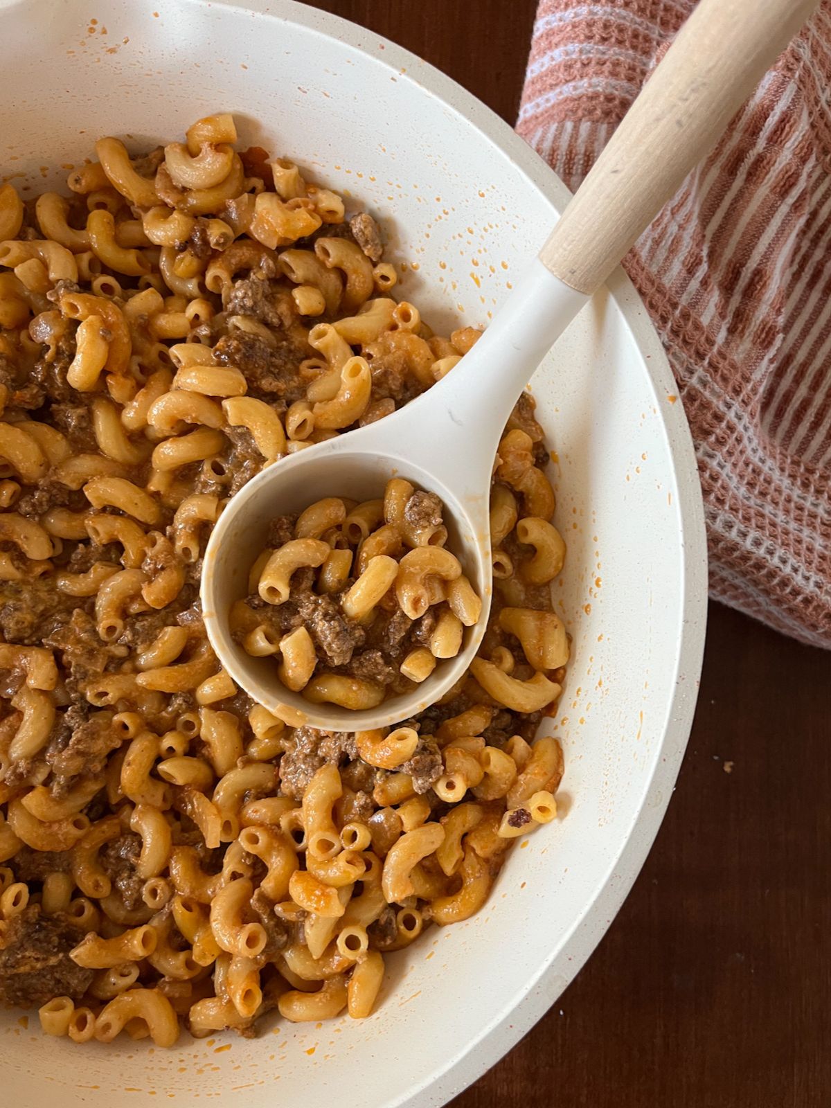 homemade hamburger helper in a large skilled with a spoon scooping it out