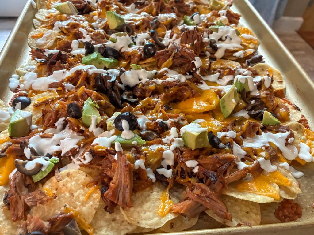 Toppings added onto pulled pork nachos