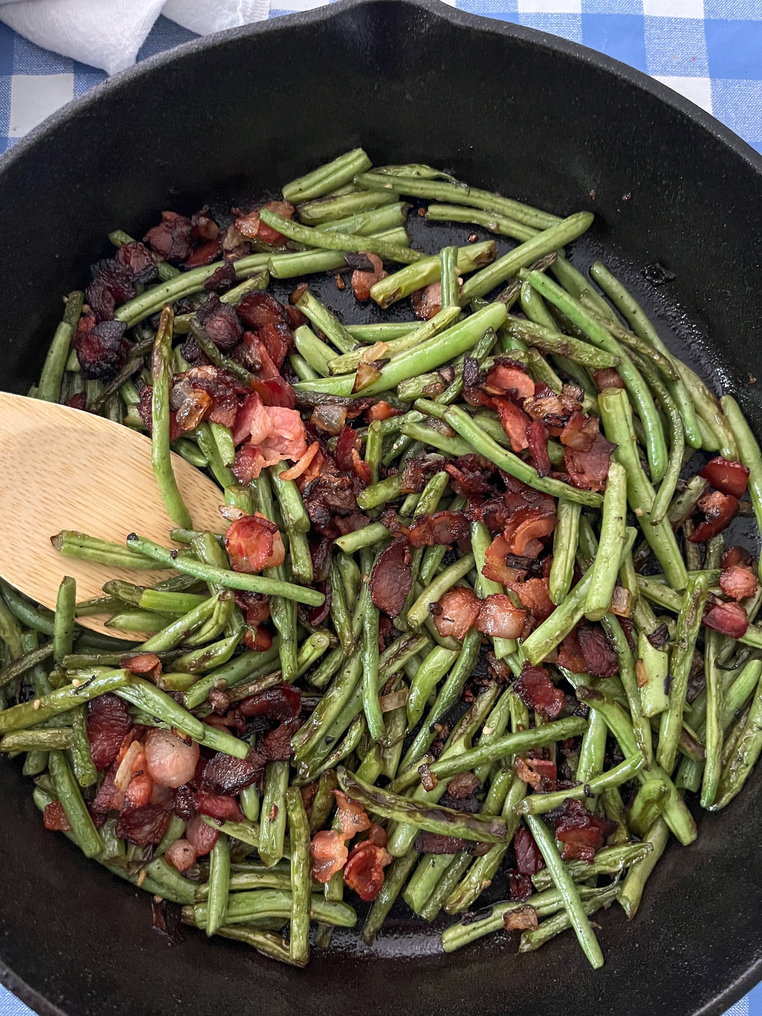 Green beans with bacon and onion in a cast iron skillet with bacon