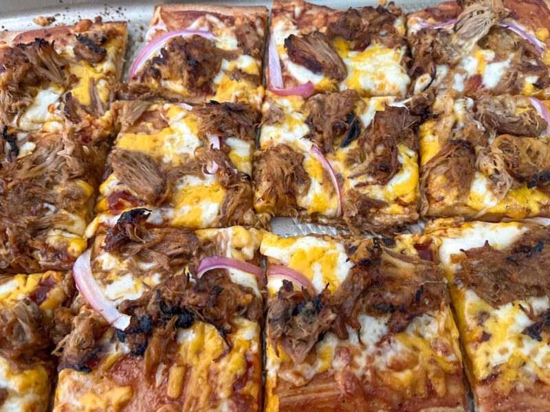 BBQ Pulled Pork pizza sliced into squares onto a serving platter