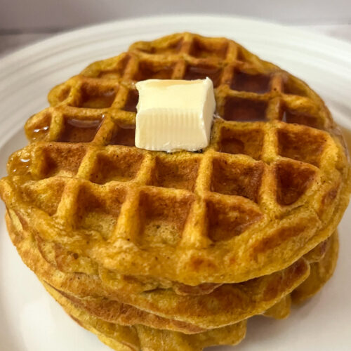 2 Pumpkin waffles with no egg stacked up with butter and maple syrup