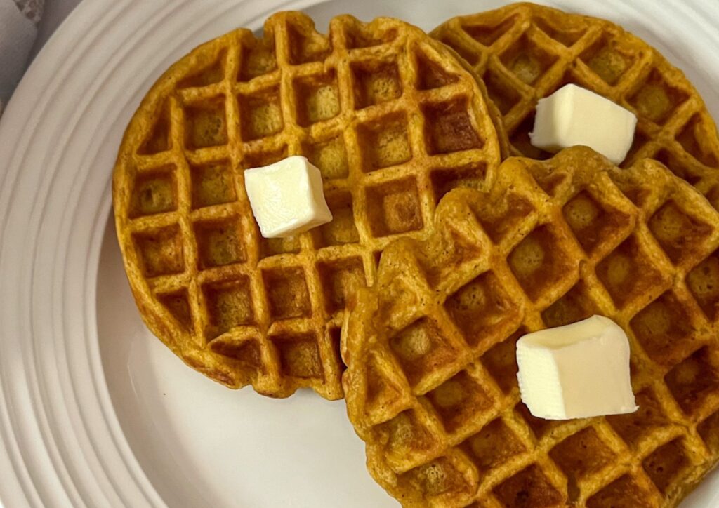 Three eggless pumpkin waffles on a plate