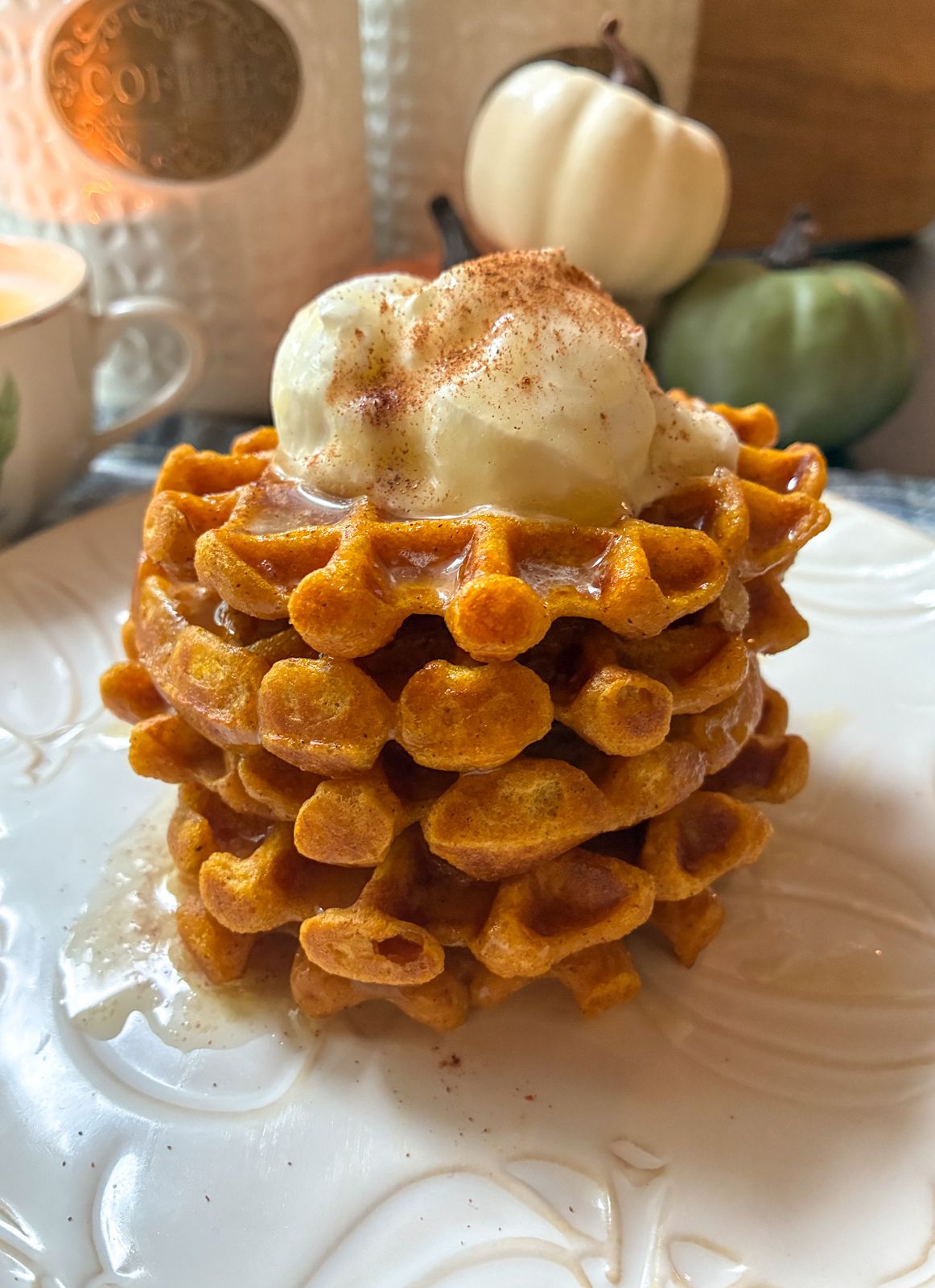 eggless pumpkin spice waffles stacked up on a plate with toppings on them