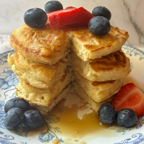 stack of eggless pancakes covered in berries and syrup