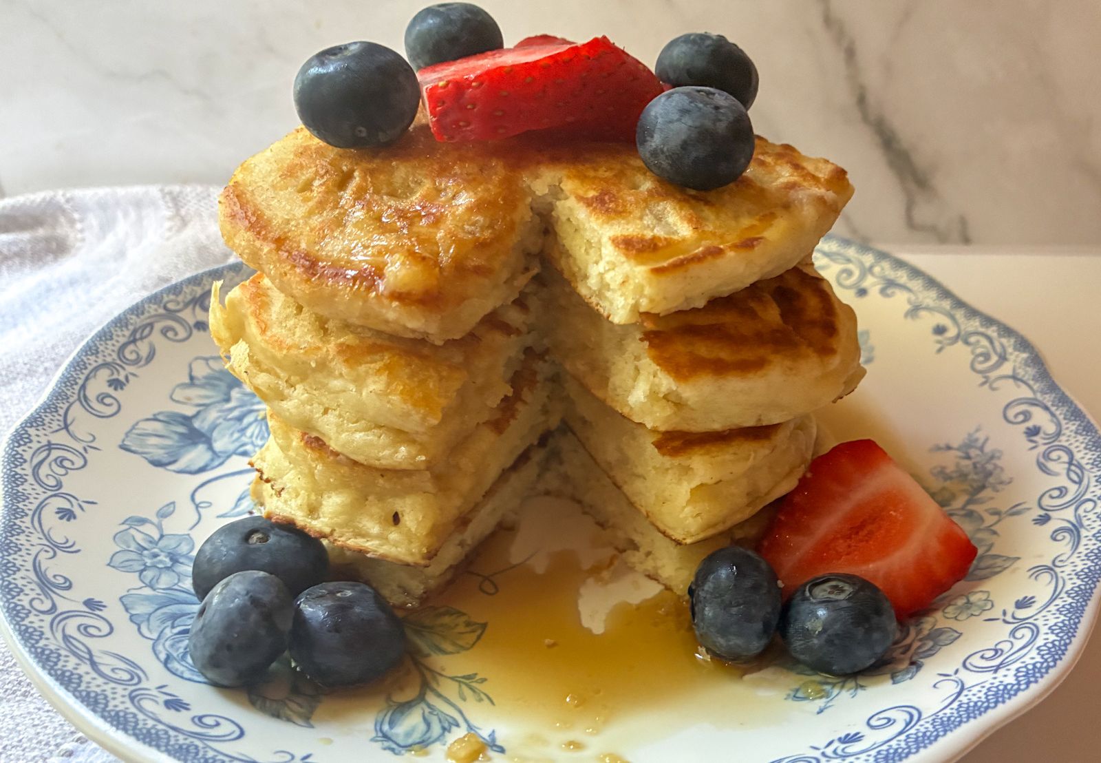 stack of eggless pancakes covered in berries and syrup