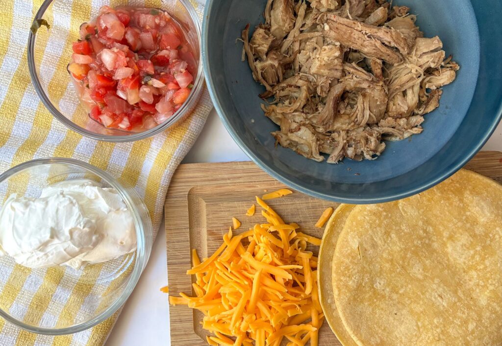 ingredients in leftover pulled pork tacos laid out on a table and on a cutting board