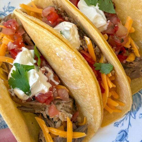 Three leftover pulled pork tacos with toppings on them
