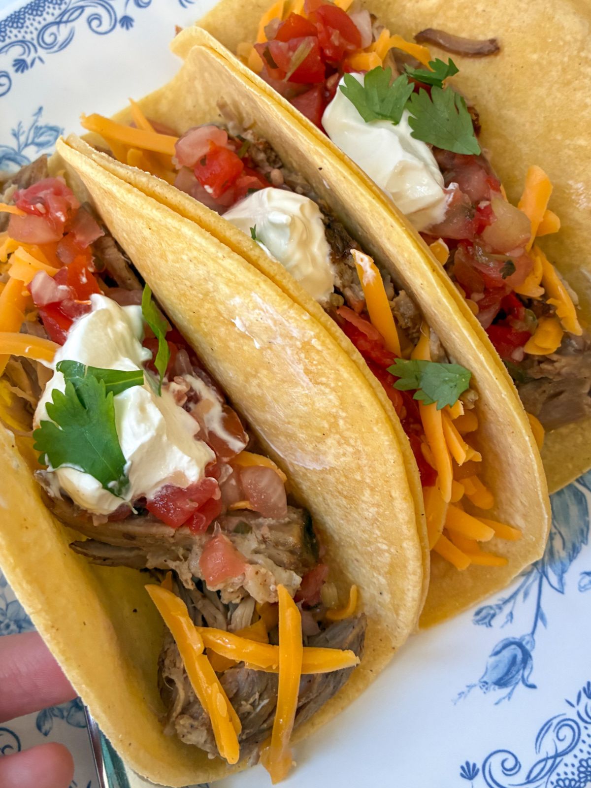 Three leftover pulled pork tacos with toppings on them