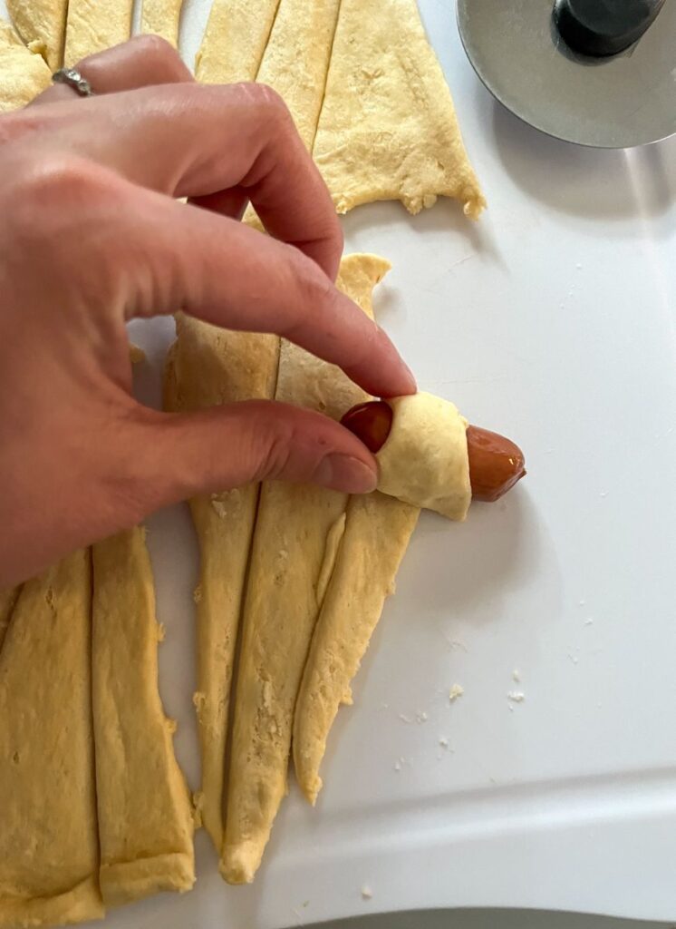 Little beef smokie being rolled up in a crescent roll