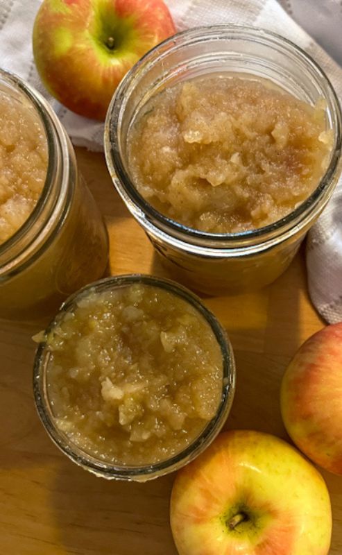 applesauce filled in mason jars surrounded by apples
