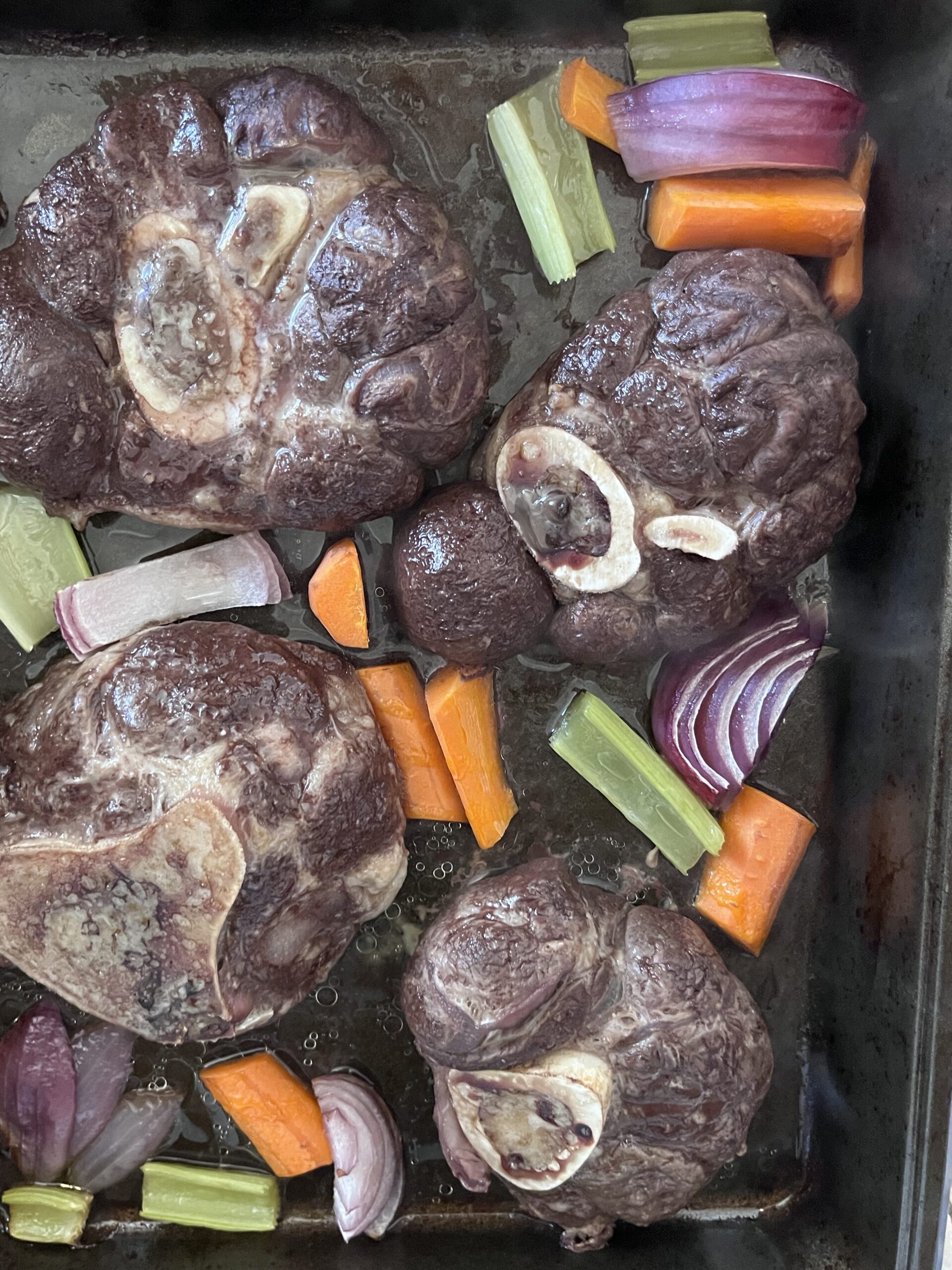 An after picture of the soup bones and vegetables after being roasted in the oven