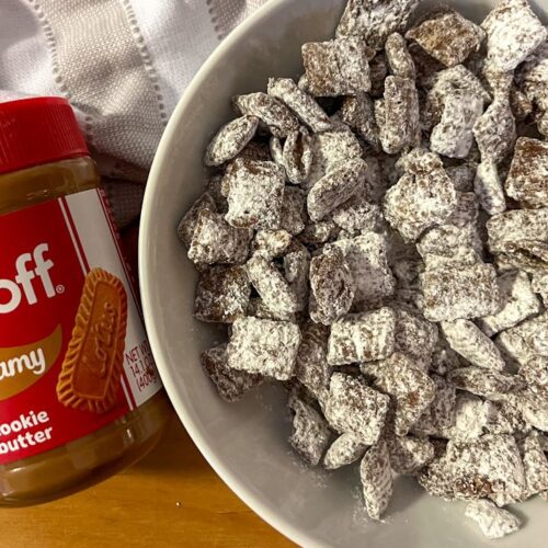 A bowl of cookie butter puppy chow with a can of biscoff cookie butter laying beside it