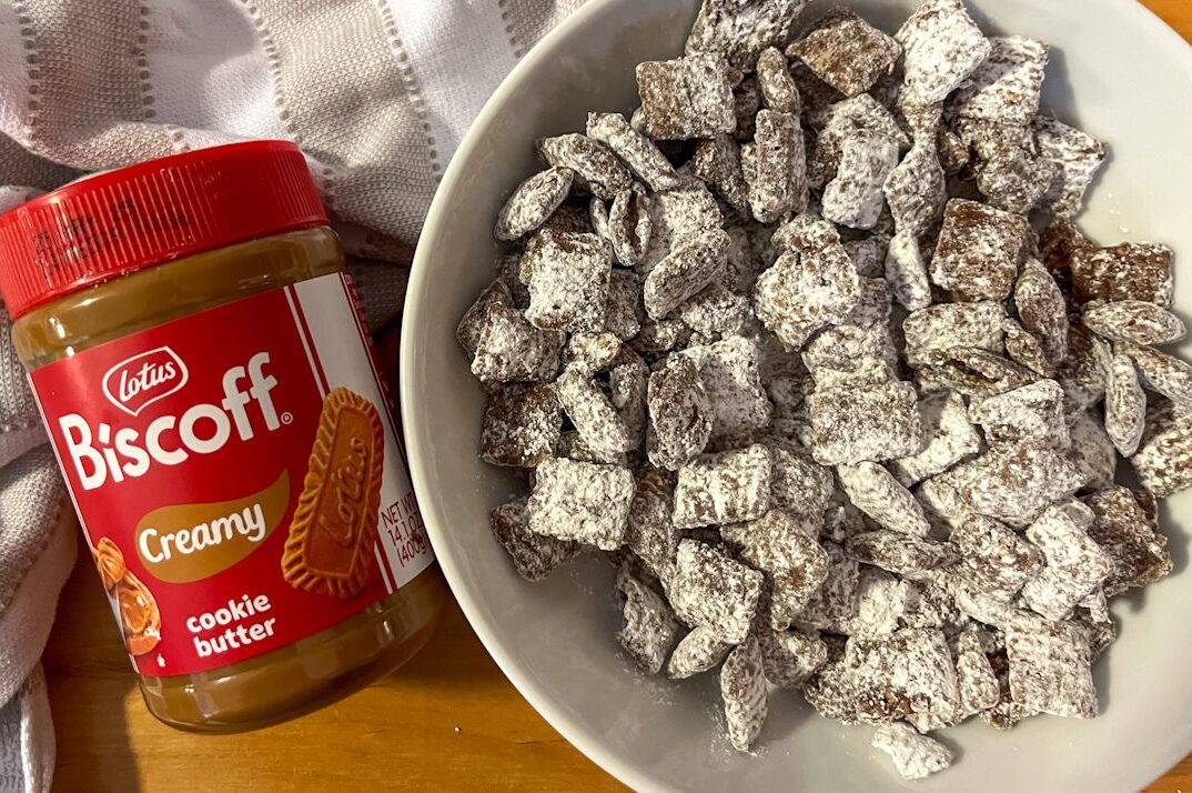 A bowl of cookie butter puppy chow with a can of biscoff cookie butter laying beside it