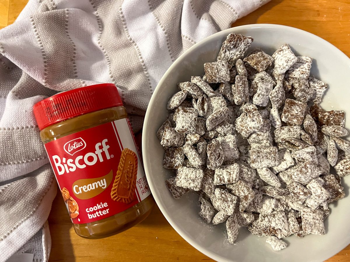 A bowl of cookie butter puppy chow with a can of biscoff cookie butter laying beside it