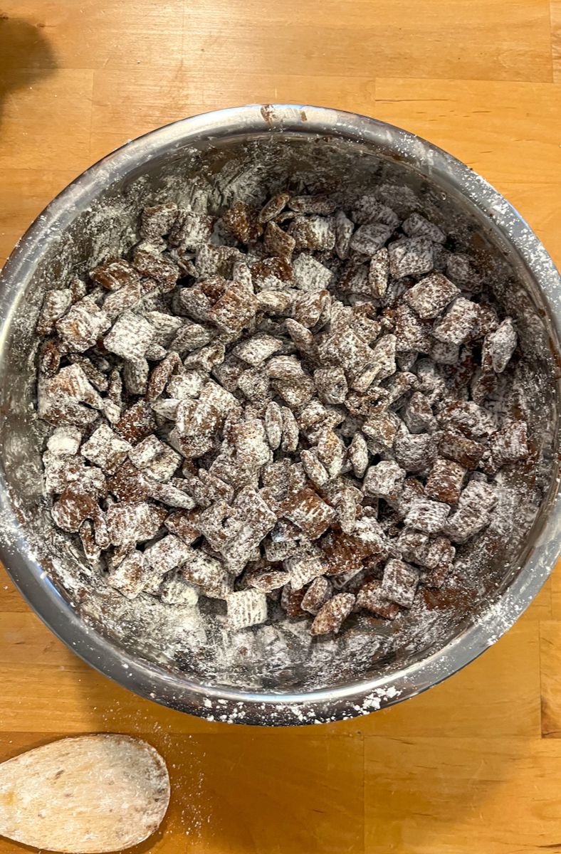 a bowl with the finished cookie butter puppy chow covered in powdered sugar