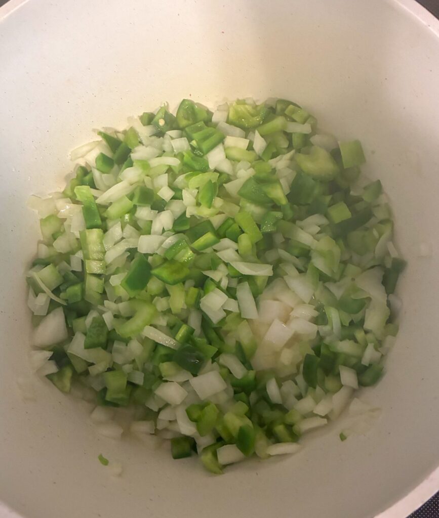 Trio of vegetables cooking in the bottom of a large pot for jambalaya