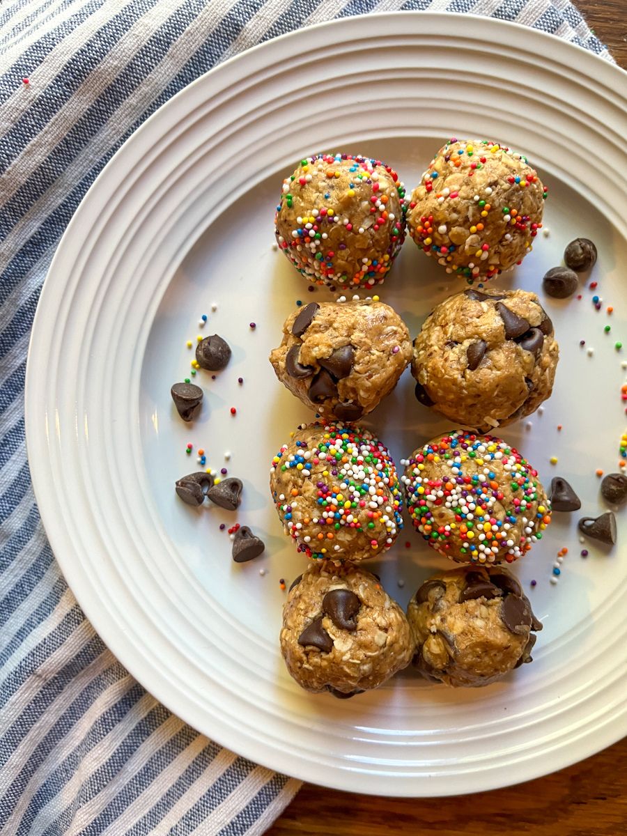 8 protein balls on a plate. Some are covered in sprinkles and others have chocolate chips