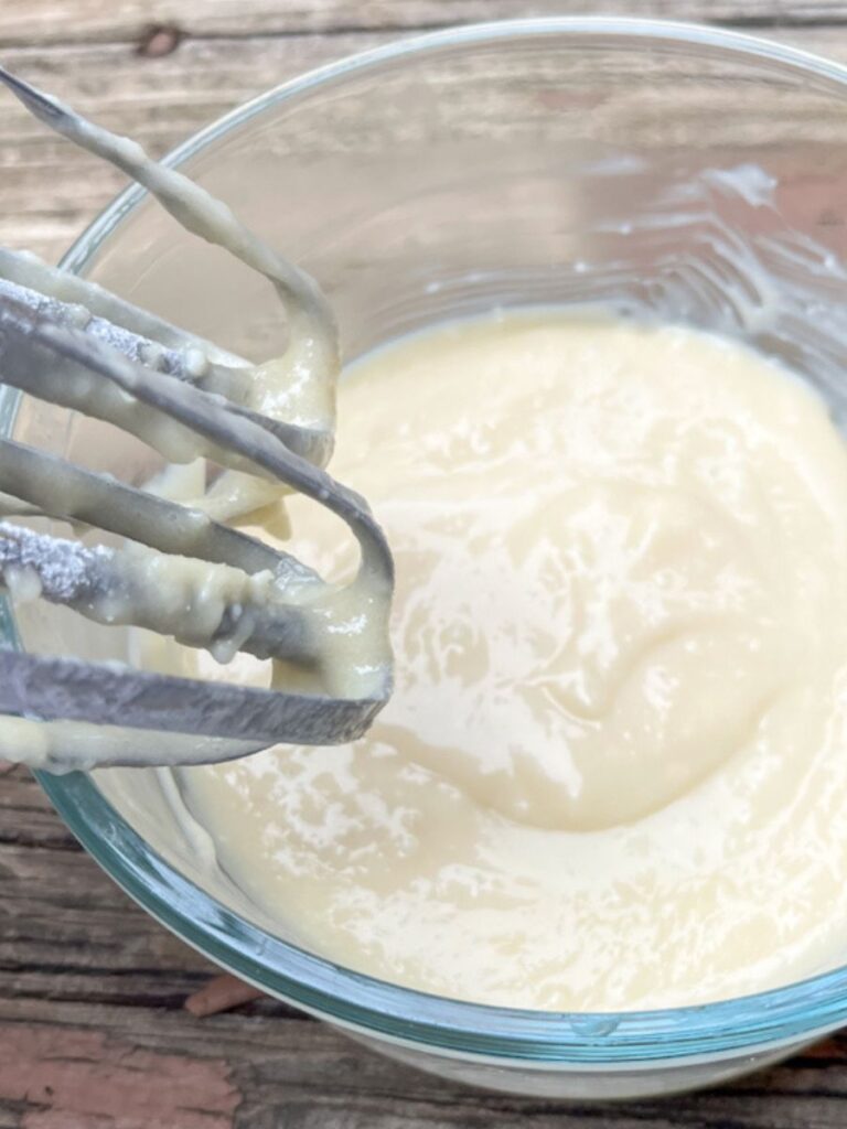 cream cheese glaze in a small bowl with a hand mixer next to it