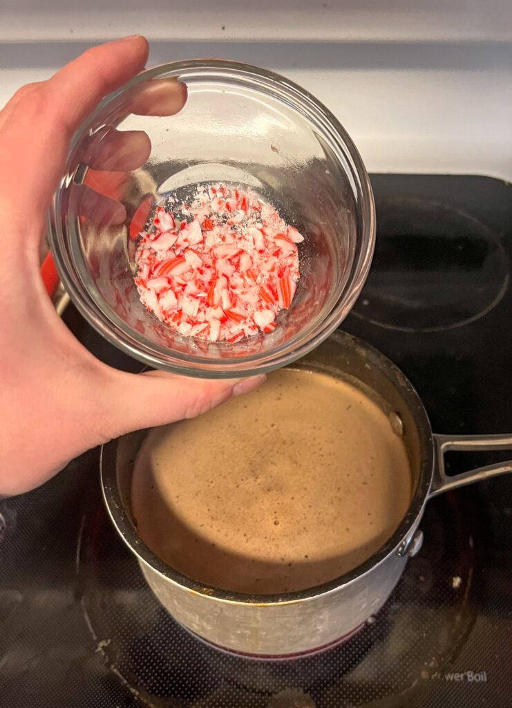 A bowl of crushed peppermint held in front of a saucepan