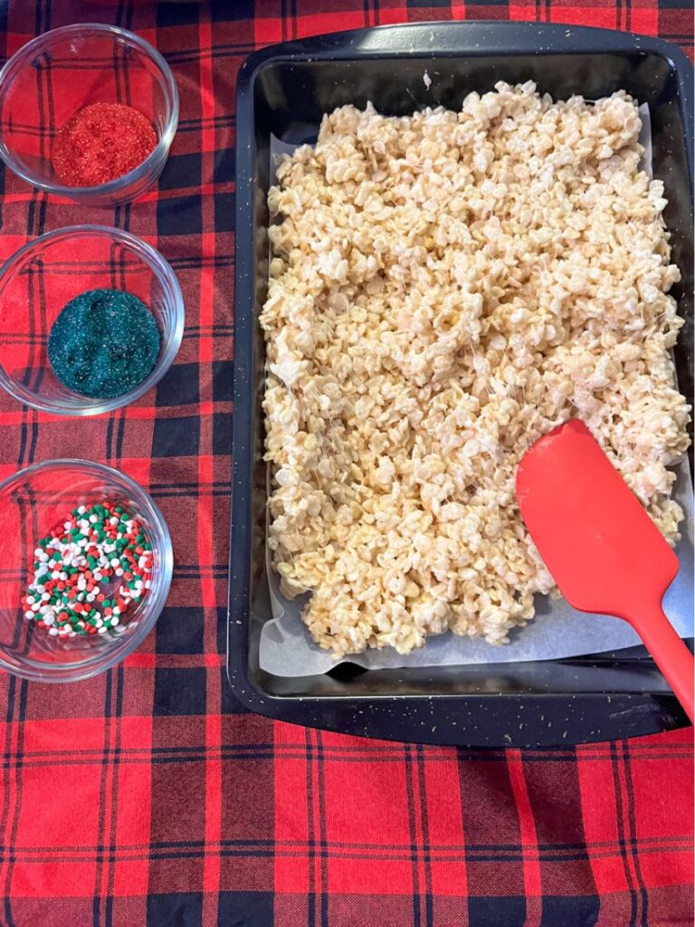 3 types of christmas sprinkles and rice krispie treats in a large pan