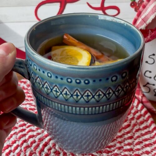 Cup with stovetop wassail and a hand holding it