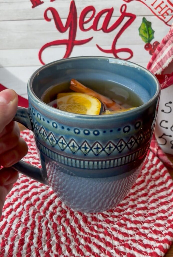 Cup with stovetop wassail and a hand holding it