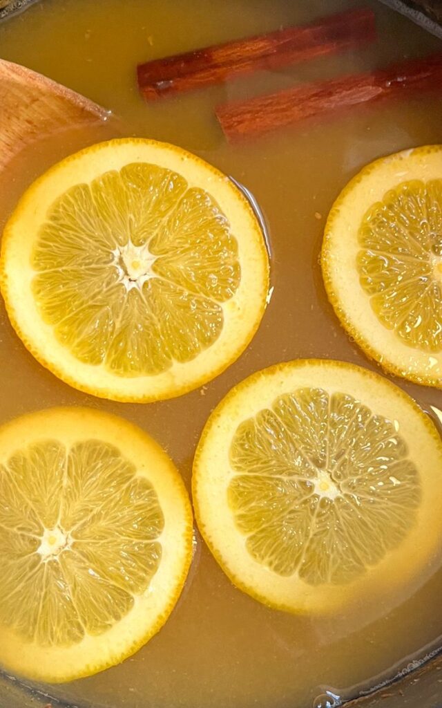 wassail in a large pot with cinnamon sticks and orang slices