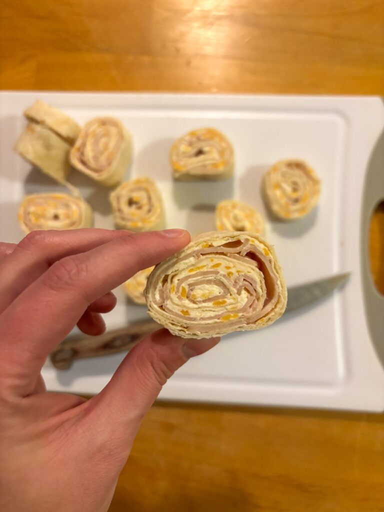 Tortilla roll ups being sliced up on a cutting board