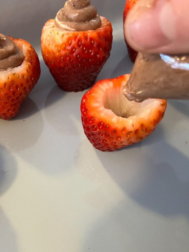 strawberries being filled with the chocolate filling