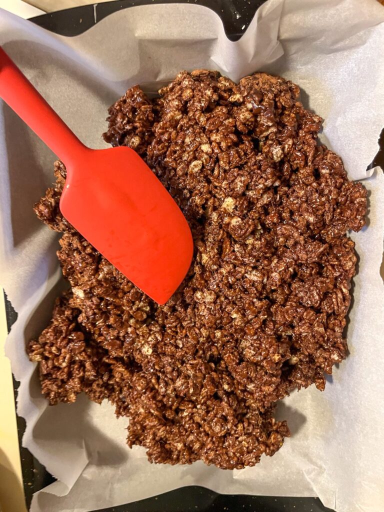 chocolate rice krispie treats being spread out in a pan