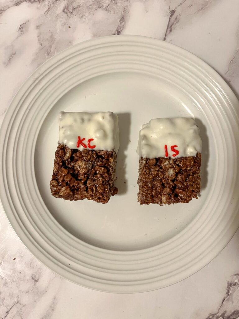 two rice krispie treats dipped in white almond bark with KC and 15 written on them