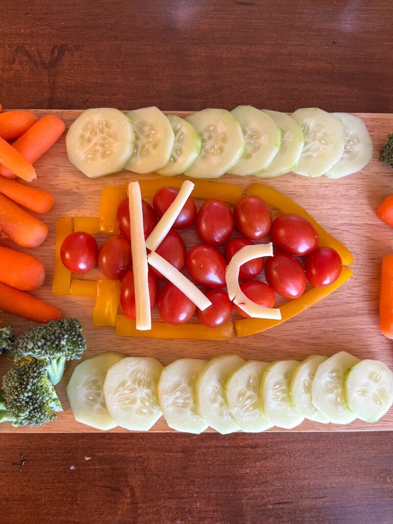 A design of kansas city football using yellow bell peppers and cherry tomatoes. The "KC" is written in cheese on top.