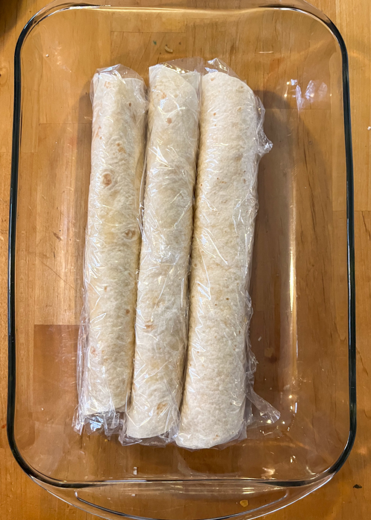 roll ups covered in plastic wrap about to go into the fridge
