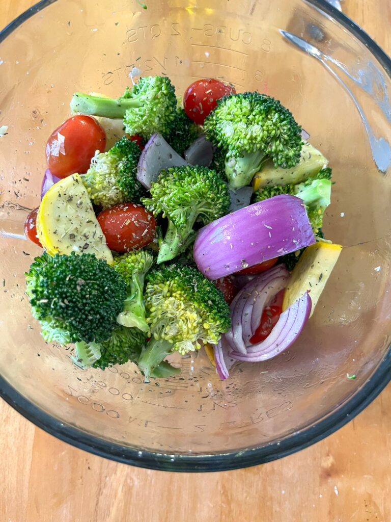 Vegetables in a large bowl tossed in oil and seasonings