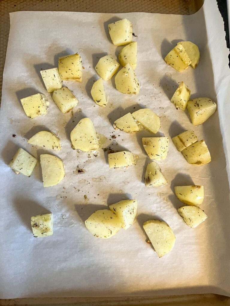 Peeled and chopped potatoes on a baking sheet prior to being cooked